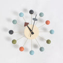 The Clock, background wall, wall clock is a modern European-style piece with a beige face and minimalist black hands. It features vibrant spherical markers in blue, orange, green, and black. Thin rods link the center to its sunburst design, making it an interior design gem.