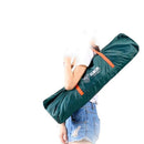In a white shirt and denim shorts, a person carries an Automatic Tent Outdoor Camping Barbecue bag—a large green bag with orange straps—over their shoulder, ideal for camping trips. The background is plain white.