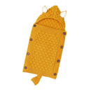The Baby sleeping bag is a knitted yellow bunting bag with a textured honeycomb pattern, plush lamb cashmere lining, hood with two white stitched ears, button closures on the side, and a small charming tail at the bottom.