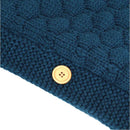 This close-up of a blue knitted fabric for a baby sleeping bag showcases raised hexagonal patterns and a wooden button with four holes, sewn on with matching blue thread, combining charm and functionality.