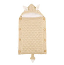 A beige knitted baby sleeping bag with a cozy lamb cashmere lining and hood featuring small animal ears. Wooden button closures on the sides complement its textured pattern, while a playful tail-like detail completes the design.