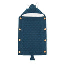 The Baby sleeping bag is a blue knitted design with a textured pattern, featuring side button closures and a hood with cute animal ears. It includes a luxurious lamb cashmere lining for warmth and comfort.