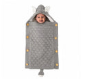A baby smiles wrapped in a cozy gray knit Baby Sleeping Bag, resembling a mouse. It features ears on the hood, button accents, a tail at the bottom, and lamb cashmere lining for comfort.