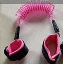 Close-up of the Child Safety Wristband, showing two black and pink padded wrist restraints linked by a coiled pink cord with anti-slip velcro for secure fastening.