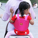 A child in a red shirt and pink backpack sits securely on a scooter outdoors, holding onto an adult in a white shirt, aided by the Child Safety Rope Motorcycle Child Safety Belt.
