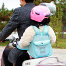 A person rides a scooter in a dark jacket with a child passenger in a furry coat secured by a Child safety rope motorcycle child safety belt. The child wears a pink helmet with visor as they journey along the paved path, surrounded by trees.