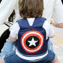 A child wearing a navy blue backpack with a circular red, white, and black superhero-like emblem is secured with the Child Safety Rope Motorcycle Child Safety Belt while being carried by an adult in a white shirt and denim shorts.