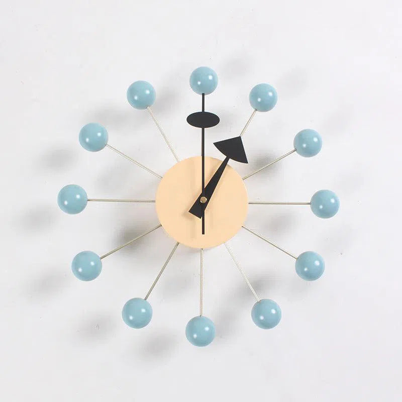 The Clock, background wall, wall clock boasts a beige circular center with black hands and metallic rods extending to light blue spheres. This mid-century modern European design fits elegantly into any interior scheme against a white backdrop.