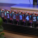 The Creative Led Electronic Digital Clock Solid Wood Nixie displays numbers 0-5 in retro Nixie style. Each tube glows with a unique neon color on a wooden base, with a laptop partially visible in the background.