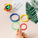 A hand holds colorful Fingertip Gyro Creative Leisure Inertia Rotation rings above a beige surface, ideal for enhancing hand-eye coordination. Nearby are more rings and intersecting structures. A card reading EVERY MOMENT MATTERS with a green leaf design partially shows, emphasizing focus.