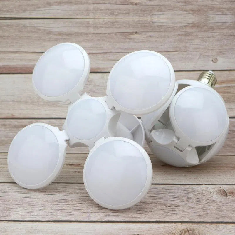 A close-up of a white, star-shaped LED bulb with circular panels in a geometric pattern. This energy-efficient light, similar to the Foldable Leaf Light Football Light LED Light, sits on a wooden surface, highlighting its innovative design.