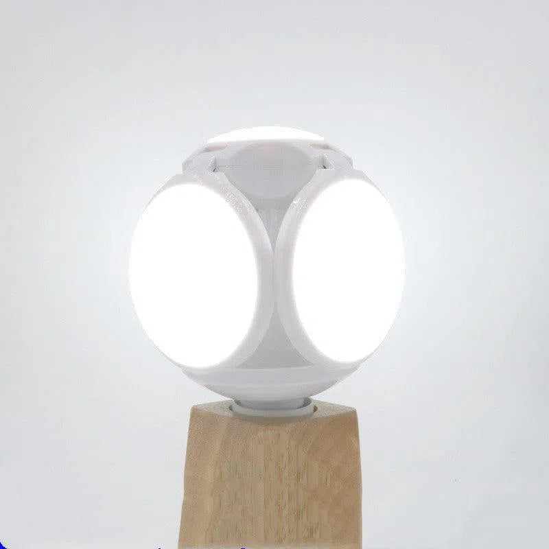 The Foldable Leaf Light Football Light LED Light features a spherical design with four glowing circular panels on a wooden base against a plain white background. Its minimalist style accentuates energy-efficient lighting, promoting a modern and sustainable aesthetic.