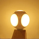 The Foldable Leaf Light Football Light LED Light, featuring spherical design and oval-shaped LEDs, emits a warm yellow glow. It stands on a wooden base, delivering energy-efficient lighting and creating a cozy atmosphere against a plain backdrop.