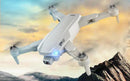 The GPS High-definition Dual Camera, a white quadcopter, gracefully captures mountain landscapes under partly cloudy skies. It hovers with GPS-guided stability, while a blue front light and four propellers enhance its aerial photography capabilities.