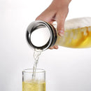 A close-up highlights a hand pouring golden beer from the Glass Kettle Heat-resistant Cool Kettle, designed with high borosilicate glass and a metallic base, into a clear glass below. The beer flows smoothly with a foamy head against a plain white background.