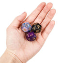A hand holds three exquisitely crafted tabletop gaming dice: a blue die with golden numbers, a black one adorned with mysterious symbols, and the Innovative Fantasy Starry Sky Resin Multi-sided Game Dice, a purple gem-like die with intricate patterns that captivate aficionados.