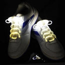 The Led Sport Shoe Laces Glow Shoe Strings, featured on white athletic shoes with blue accents, use advanced fiber-optic technology. These round flash light shoelaces emit a bright yellow glow, enhancing contrast against dark backgrounds.