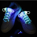 White sneakers with LED Sport Shoe Laces Glow Shoelaces in green and blue create a vibrant, eye-catching effect against a dark background.