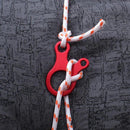 A red rope cleat on dark textured fabric, featuring an aluminum alloy cleat for durability. The orange-accented rope, part of the Outdoor camping snail wind rope buckle, is looped and knotted to show secure outdoor attachment, ideal for camping.