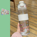 A hand holds the Portable Large Capacity Plastic Cup, featuring a clear body with a white lid and grip, adorned with cute animal stickers. Ideal for daily hydration, its design is convenient. To the left, similar stickers are shown on a green background above a wooden floor.