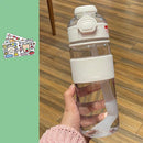 A person in a pink knitted sweater holds the Portable Large Capacity Plastic Cup, a clear water bottle with a white lid, grip, and internal straw for all hydration needs. Its known for temperature resistance. To the left, cartoon character stickers brighten a green background.