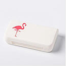 White rectangular portable pill storage box featuring a pink flamingo graphic on the lid, set against a plain background.