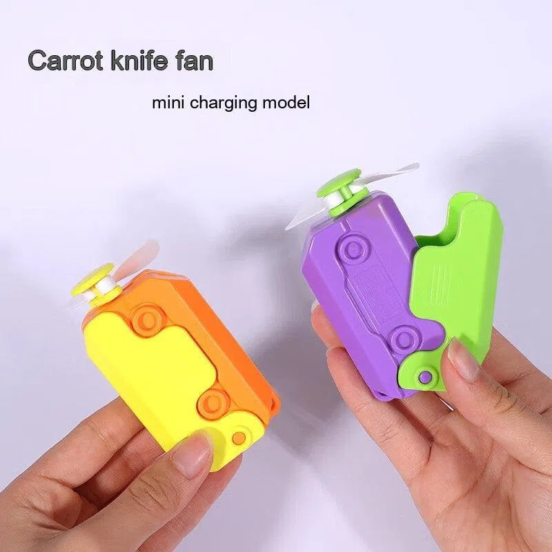 Two hands hold vibrantly designed Radish Knife Mini-portable Handheld Fans resembling box cutters. One fan is orange and yellow, the other is purple and green. Each has small propellers protruding. Text reads Carrot knife fan and mini charging model.