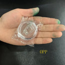 A hand with green-stained fingers holds a clear circular plastic container wrapped in plastic, labeled OPP on the black surface beneath. Inside is a Silicone Magnetic Anti Snore Stop Snoring Nose Clip Sleep Tray Sleeping Aid Apnea Guard Night Device.
