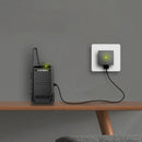 A black TIENGU Professional Wireless Handheld Intercom Radio with LED flashlight sits on a wooden shelf, linked to a wall charger glowing green to show its on, blending seamlessly with the minimalist design.