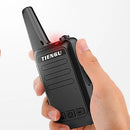 A hand holding a black TIENGU Professional Wireless Handheld Intercom Radio, featuring a long antenna, a red light at the top, and several side buttons.