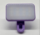 The Mini Selfie Fill Light is a rectangular, purple, rechargeable LED lamp with adjustable 3 color modes, a clip-on design for phones or computers, and a white frosted cover. Made from durable ABS, it’s perfect for photography against any background.